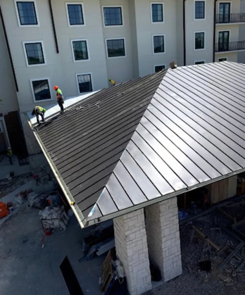 Crew installing standing seam metal roof panels on a commercial project in East Lyme